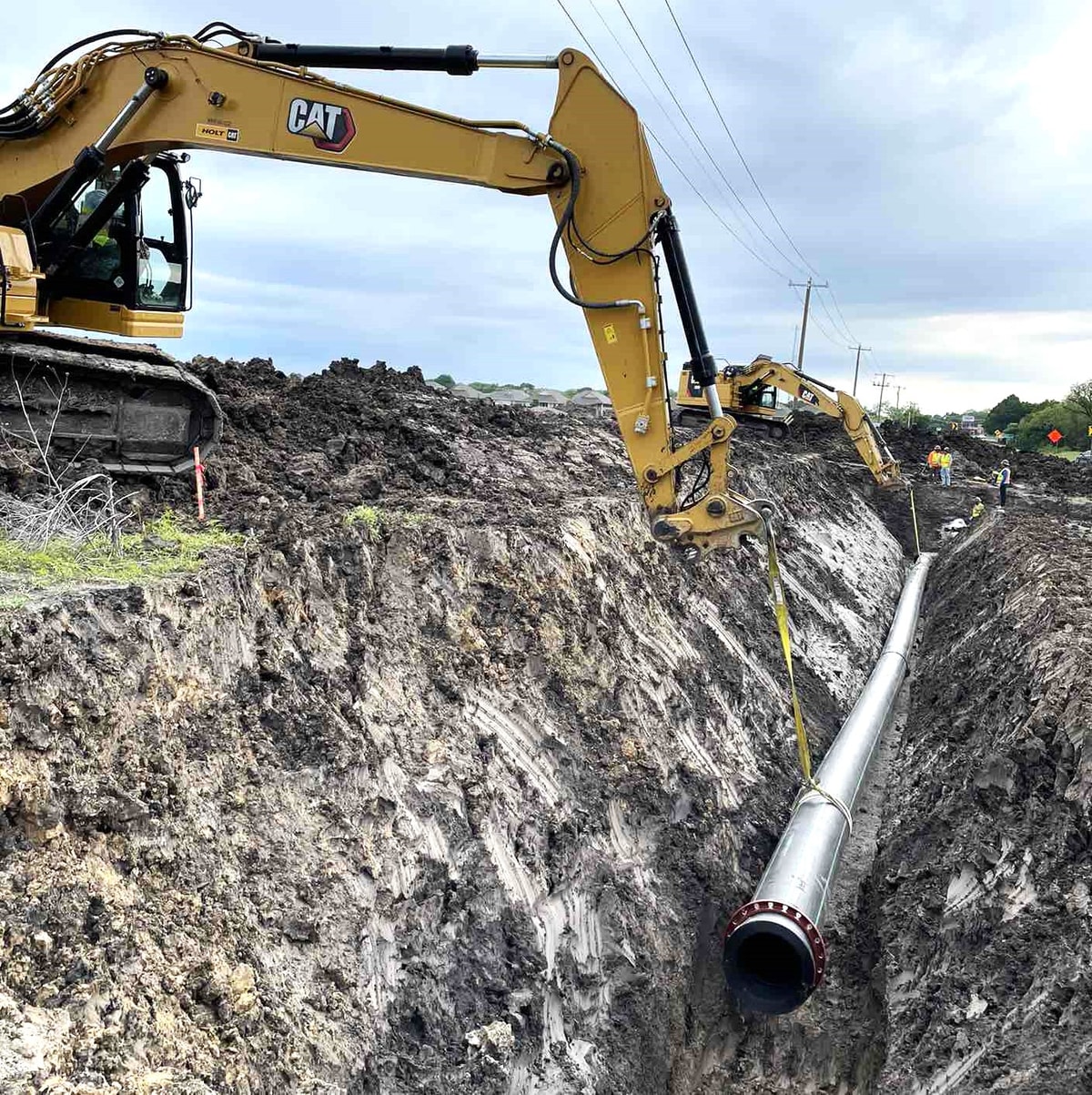 Excavator laying a sewer main in an open trench