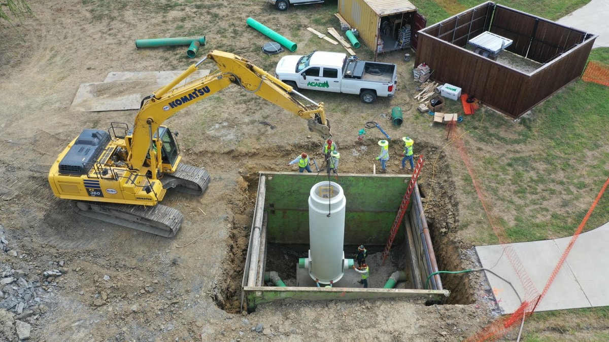 Excavator setting a metered manhole vault