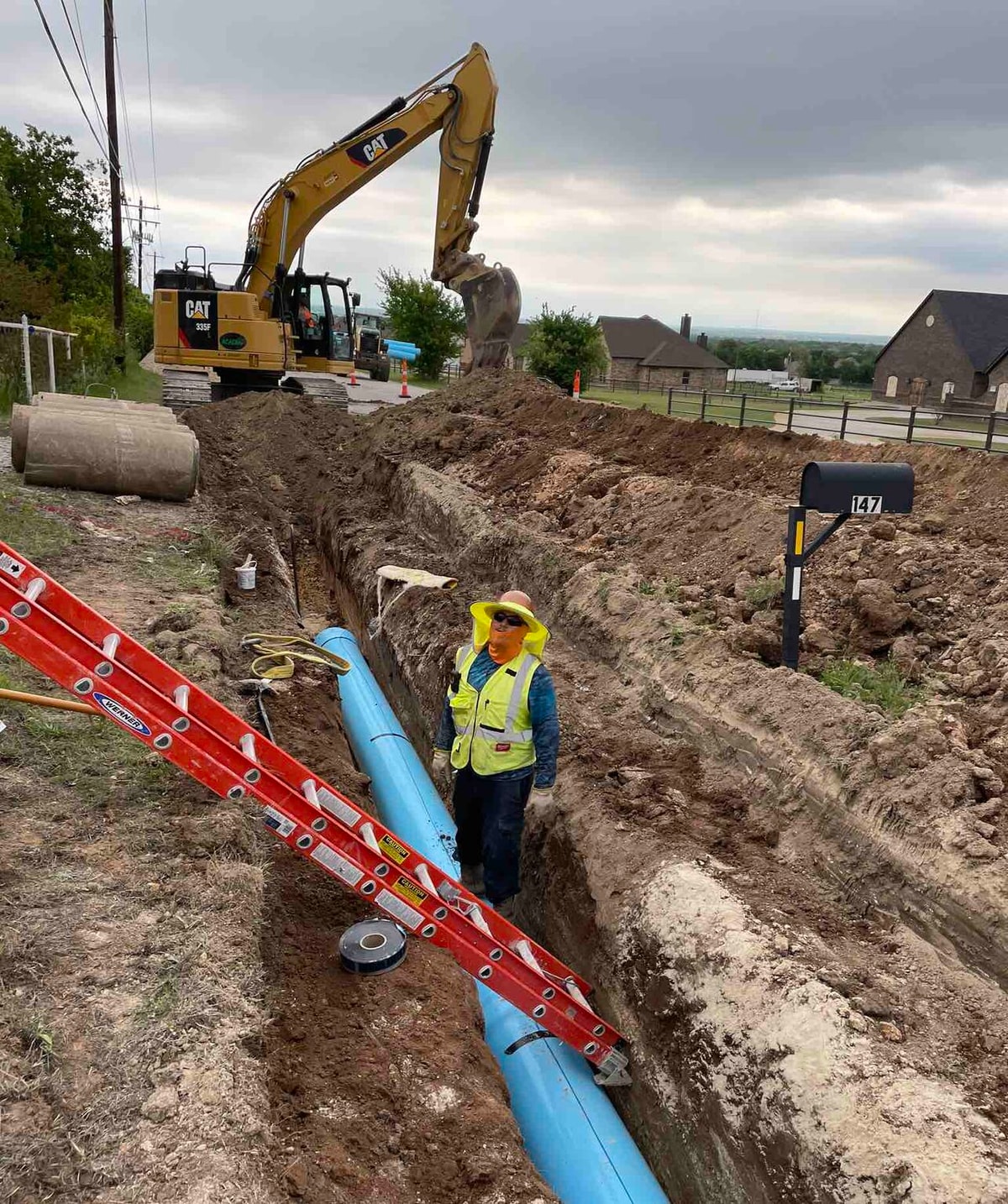 Crew installing blue water line pipe in a trench