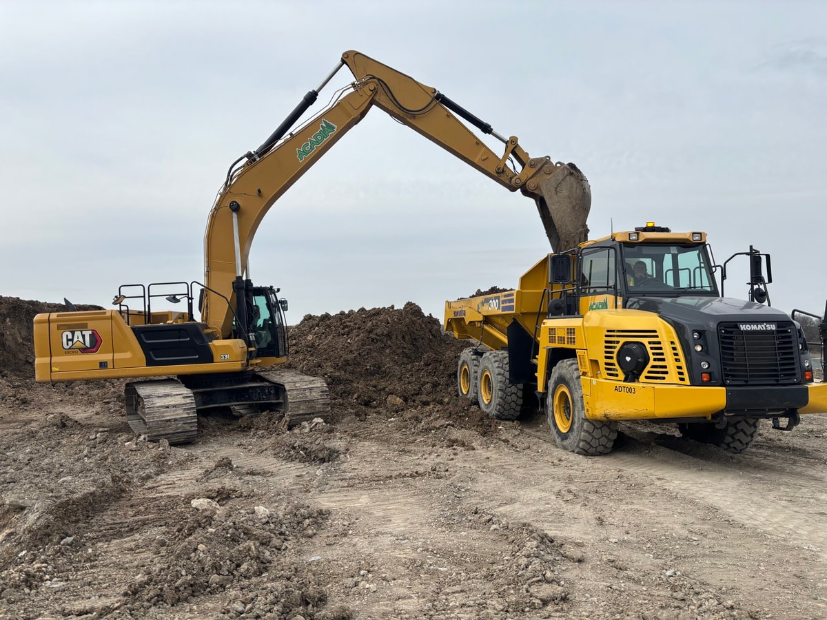 Excavator and haul truck on an Acadia job site